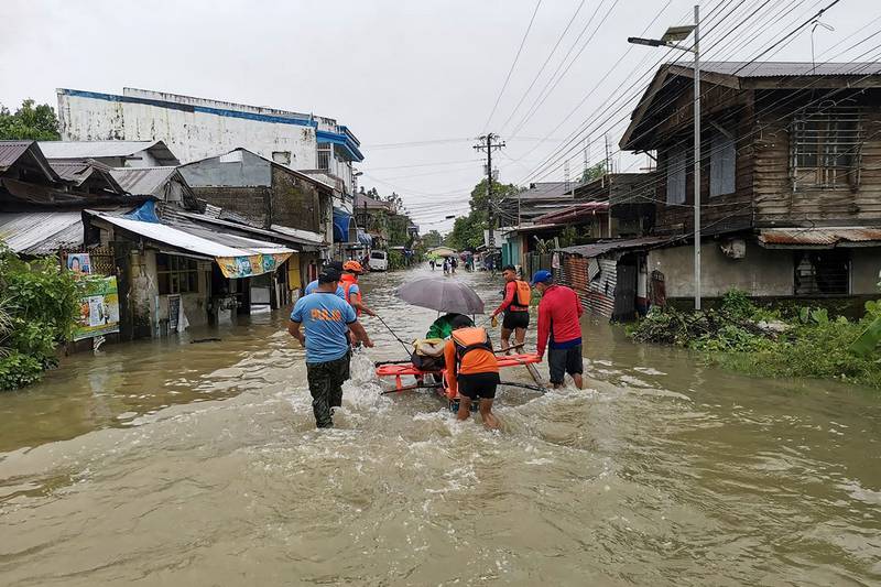 Coastguards and police help a resident to safety after severe flooding in Abuyog, southern Philippines.