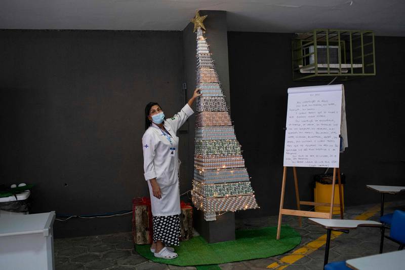 A health professional points to a Christmas tree made with Covid-19 and flu vaccine vials at the Public Health Basic Unit 'Ernani Agricola' in the Lapa neighborhood in Rio de Janeiro, Brazil. AFP