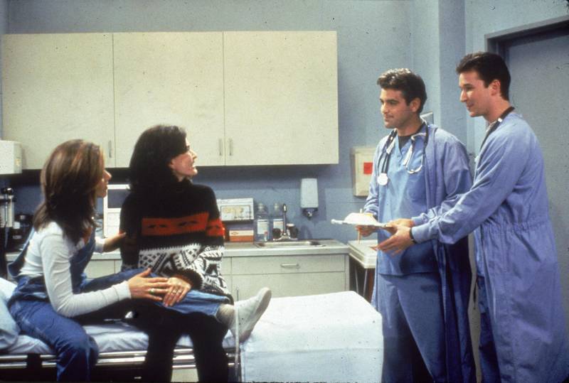L-R: Jennifer Aniston and Courteney Cox sit in a hospital room, speaking to guest stars George Clooney and Noah Wyle from 'ER' in a still from the television series, 'Friends,' circa 1996. (Photo by Fotos International/Getty Images)
