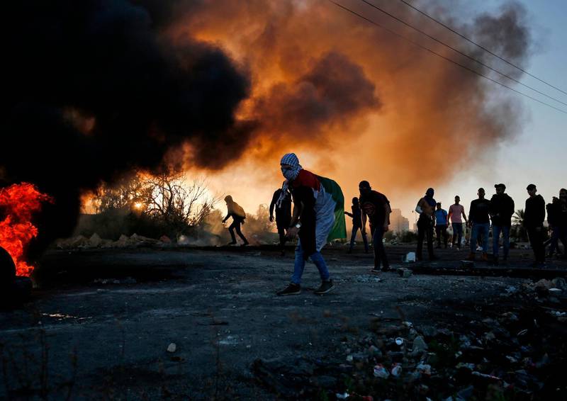 Palestinian protesters stand amid smoke during clashes with Israeli troops in Ramallah. AFP