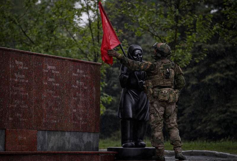 A Russian serviceman adjusts the Soviet flag on a statue in Leninsky Komsomol Square in Mariupol, Ukraine. EPA