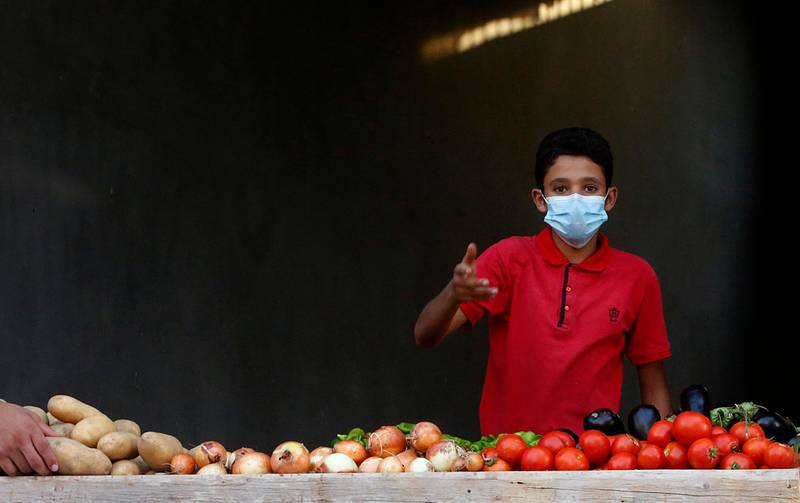 A Palestinian boy sells vegetables while wearing a face mask during a lockdown imposed following the discovery of coronavirus cases in Gaza City. AP Photo