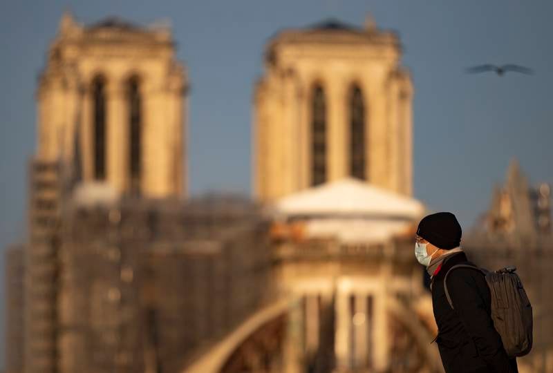 A pedestrian wearing a protective face mask walks near Notre-Dame Cathedral, in Paris.  Nearly 57,000 new Covid-19 infections are being reported in France every 24 hours. EPA