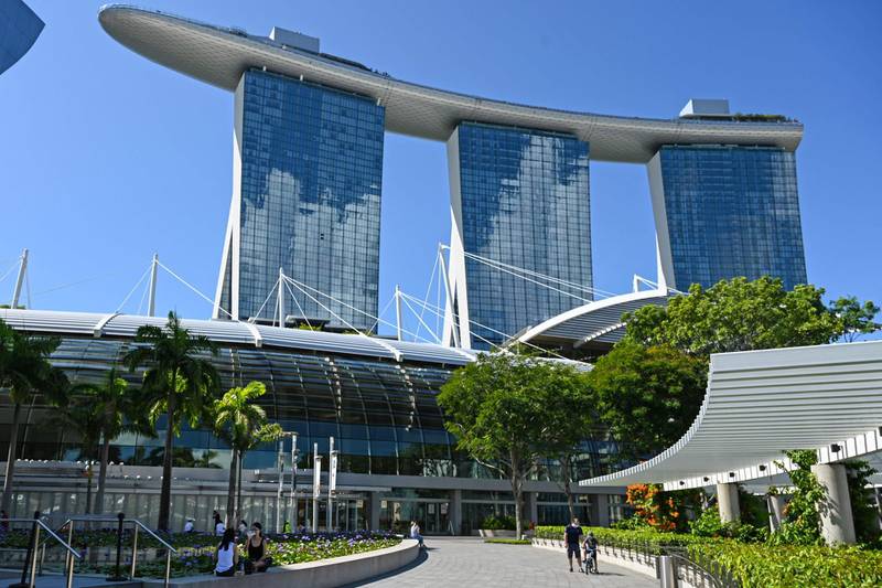 This photograph taken on June 14, 2021 shows people sitting next to a pond outside the Marina Bay Shoppes shopping centre in Singapore.  A financial exchange offering carbon credits and investments in conservation projects is set to launch in Singapore, but it may struggle to convince sceptics of the value of controversial carbon offsets.  - TO GO WITH Singapore-market-climate, FOCUS by Martin Abbugao and Sam Reeves
 / AFP / Roslan RAHMAN / TO GO WITH Singapore-market-climate, FOCUS by Martin Abbugao and Sam Reeves
