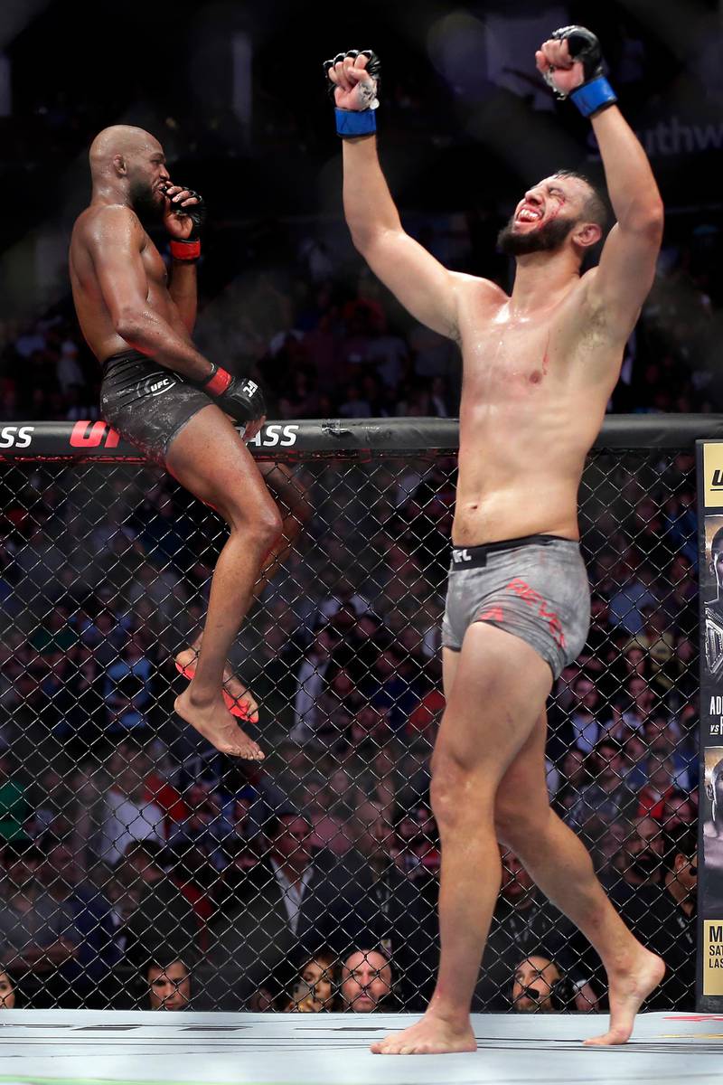 Jon Jones, left, sits on the fence as Dominick Reyes, right, celebrates after their light heavyweight title match at UFC in Houston. AP