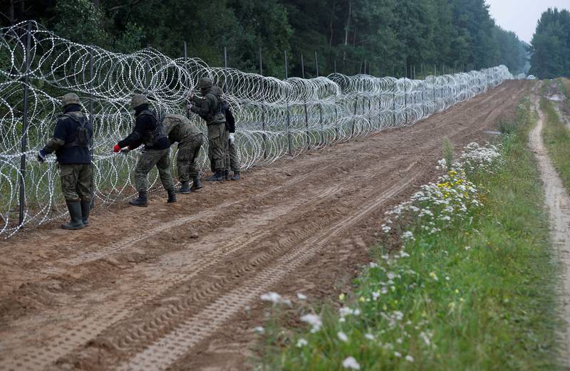 Polish soldiers build a fence on the border with Belarus, near the village of Nomiki. Reuters