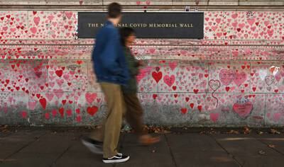 Pedestrians pass the National Covid-19 Memorial Wall, opposite the Palace of Westminster, in London. EPA