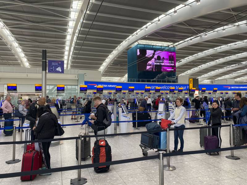 Passengers queue to check in at Heathrow Airport in London. PA