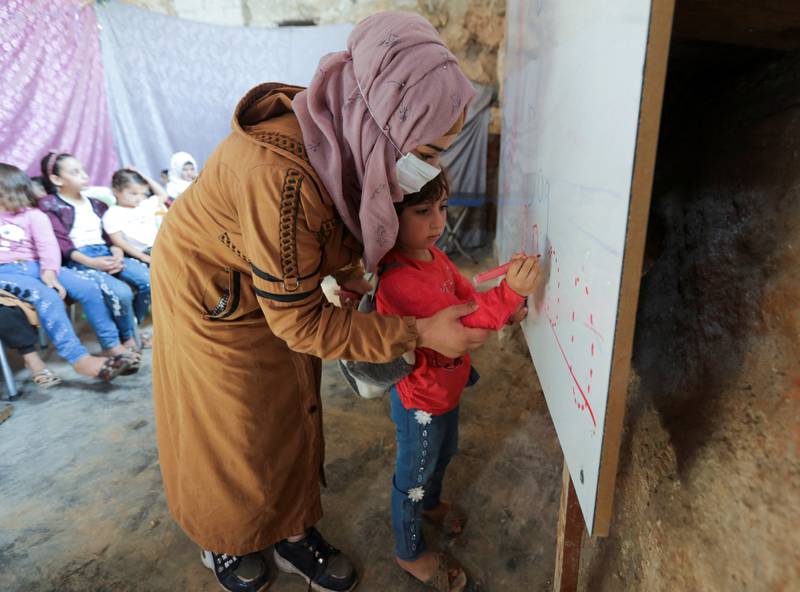 A teacher helps a pupil to write on a board during a lesson.