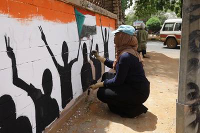 A young Sudanese woman paints a wall. EPA