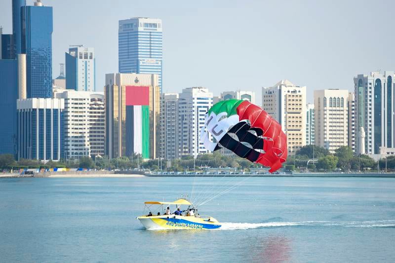 Parasailing with the flag colours on the UAE's 51st National Day, off the Abu Dhabi Corniche. Khushnum Bhandari / The National
