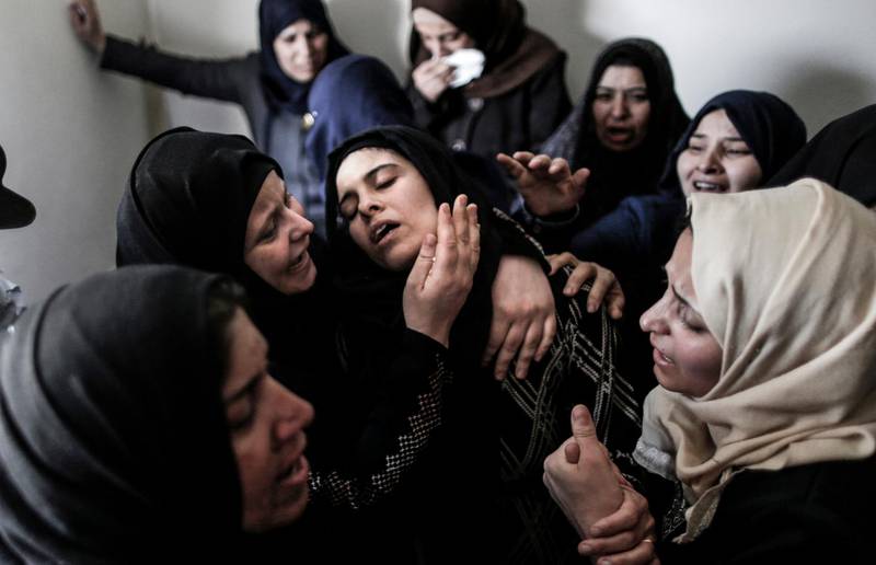 TOPSHOT - Mourners console the mother (C) of 15-year-old Palestinian teenager Azzam Oweida during his funeral in Khan Yunis in the southern Gaza Strip on April 28, 2018, as he succumbed to his wounds a day after he was shot by Israeli forces in clashes along the Gaza border. / AFP PHOTO / MAHMUD HAMS