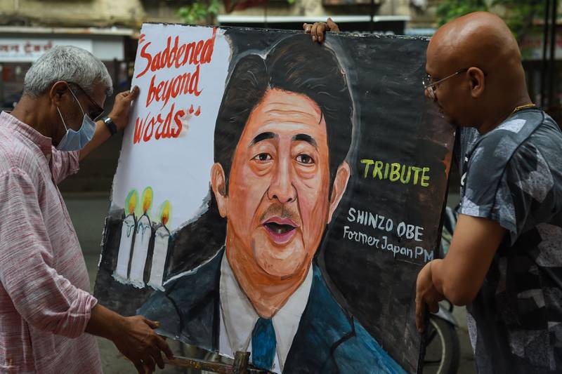 Artists carry a painting of Mr Abe in Mumbai. AFP