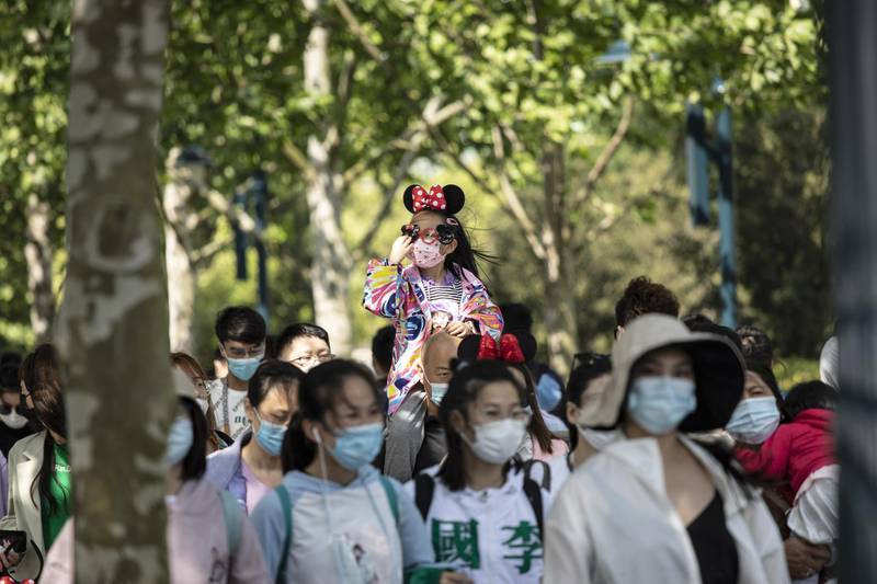 Visitors wearing masks walk towards the entrance of Shanghai's Disneyland theme park. Travel and hotel bookings for China's five-day break that began on May 1 have all surged, beating those for the same period in 2019, according to Trip.com. Bloomberg