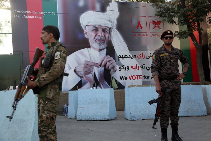 In this Monday, Sept. 23, 2019 photo, Afghan security forces stand guard in front of an election poster for presidential candidate Ashraf Ghani in Kabul, Afghanistan. Millions of Afghans are expected to go to the polls on Saturday to elect a new president, despite an upsurge of violence in the weeks since the collapse of a U.S.-Taliban deal to end Americaâ€™s longest war, and the Taliban warning voters to say away from the polls. (AP Photo/Rahmat Gul)