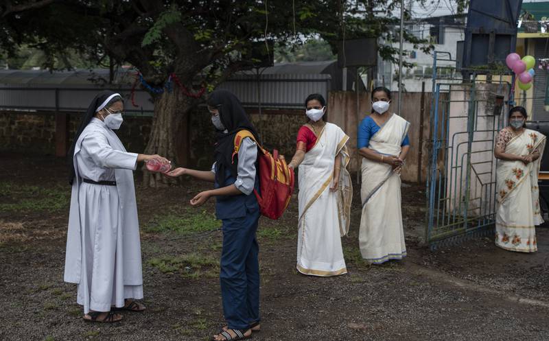 A teacher offers hand sanitiser to a pupil as a precaution against Covid-19 as schools reopen in Kochi, in Kerala state, India. All photos: AP