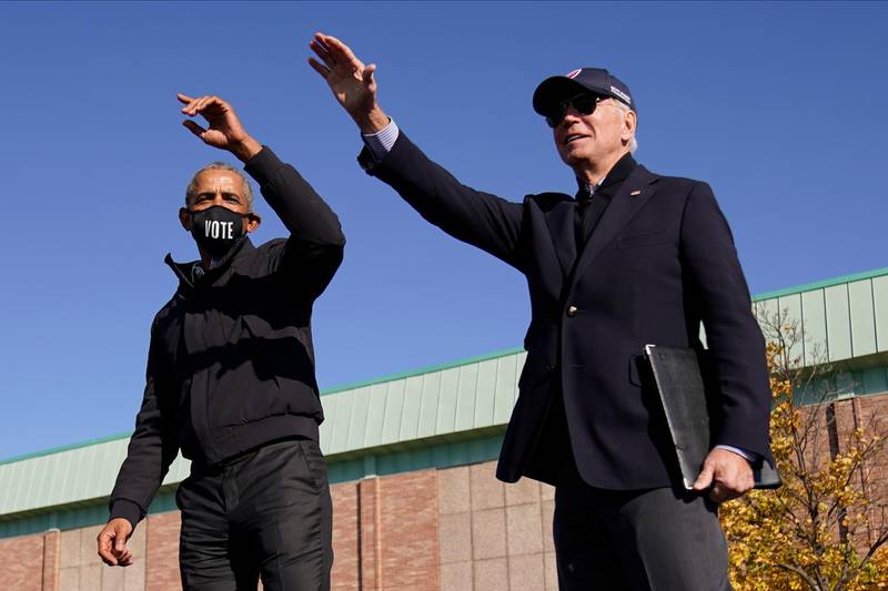 Democratic presidential candidate former Vice President Joe Biden, right, and former President Barack Obama, left, on stage together waving to the audience at a rally at Northwestern High School in Flint, Michigan.  AP