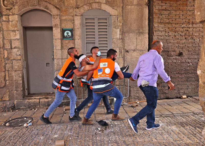 Palestinian medics carry a wounded protester at the Damascus Gate in Jerusalem's Old City on May 10, 2021. AFP