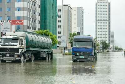 Lorries slowly make their way on a heavily flooded road in the city. Khushnum Bhandari / The National

