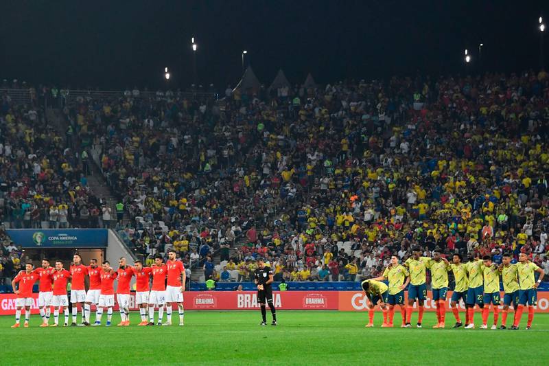 Chile and Colombia players stand on the halfway line during the penalty shootout. AFP