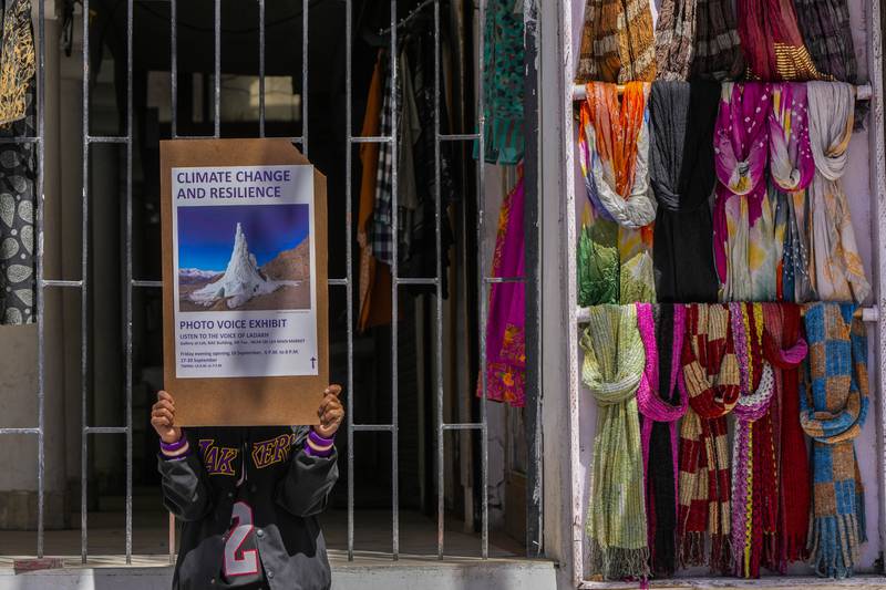 A climate activist holds a placard to advertise a local photo exhibition on climate change in Leh town.