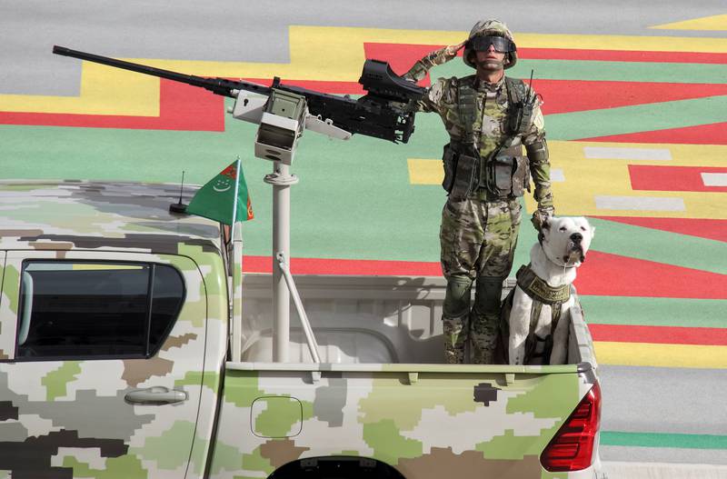 A soldier salutes as he rides with a dog in a pickup during the parade.