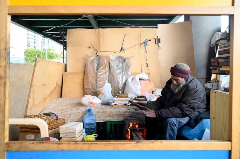 Mohammed Maghrabi warms himself under the bridge before the fire that devastated his shelter.