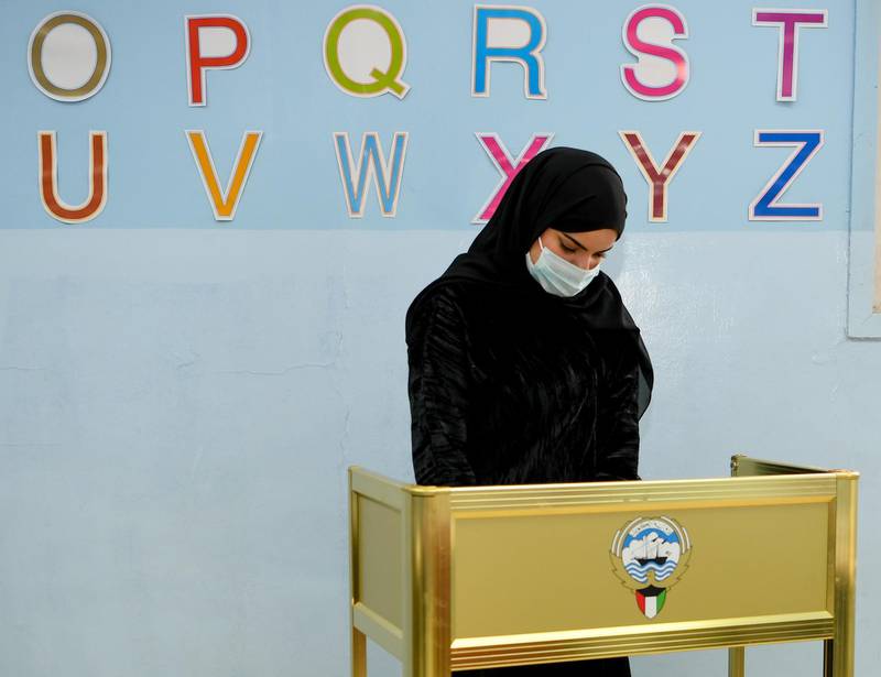 A Kuwaiti woman wearing a protective mask cast her vote at a polling station in Kuwait City. EPA