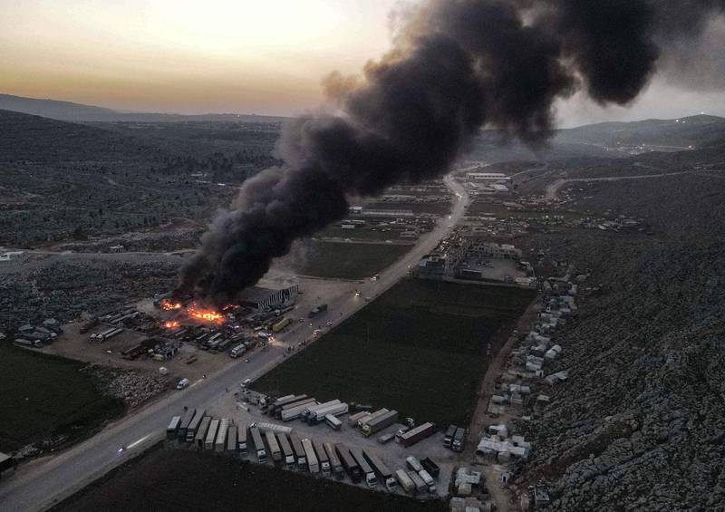 An aerial view of a billowing smoke plume coming from burning trucks and freight vehicles in the aftermath of air strikes at a depot near the Bab al-Hawa border crossing between Syria and Turkey in Syria's rebel-held northwestern Idlib province.  AFP