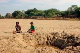 Children by a dug out water hole in a dry river bed in the village of Fenoaivo, in Madagascar. AP