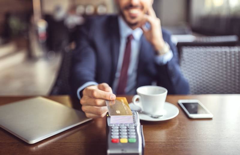 Smiling man at coffee break paying with credit card 