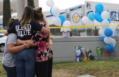 SANTA CLARITA, CALIFORNIA - NOVEMBER 15: A Saugus High School student (2nd L) is embraced as she visits a makeshift memorial in front of the school for victims of the shooting there on November 15, 2019 in Santa Clarita, California. The shooting left two students dead and others wounded while a suspect in the shooting is being treated at a local hospital for a gunshot wound to the head.   Mario Tama/Getty Images/AFP
== FOR NEWSPAPERS, INTERNET, TELCOS & TELEVISION USE ONLY ==

