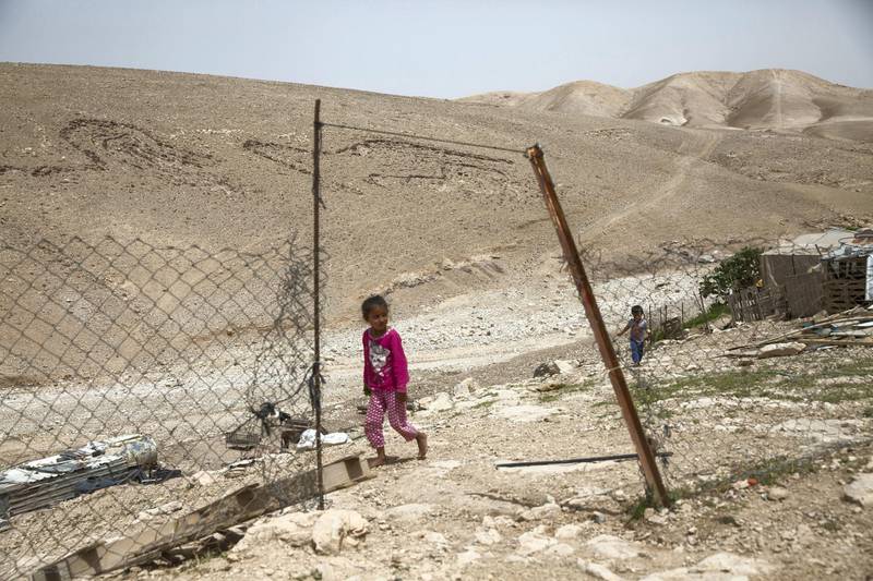 A young child is seen passing the entrance of a home in the tiny West Bank Beduin village of Khan al-Ahmar  on May 2,2018.The Israeli Supreme Court is expected next week to rule on the fate of the village, situated east of Jerusalem between the expanding settlements of Maale Adumim and Kfar Adumim.  The Israeli state says Khan al-Ahmar must be leveled because its structures are situated on state land and were built without permits, which are nearly impossible to obtain in the part of the West Bank known as area C, under full Israeli control.(Photo by Heidi Levine for The National).