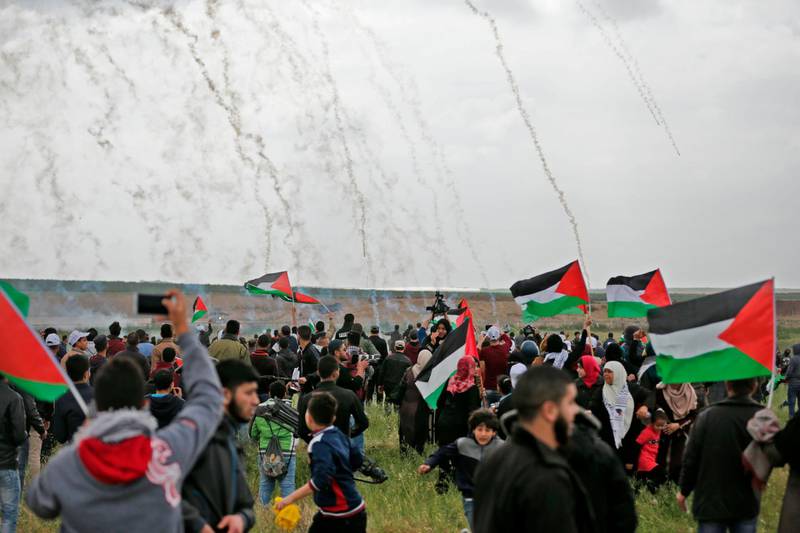 Palestinians flee as Israeli tear gas grenades begin to drop on a demonstration near the Gaza Strip's border with Israel on March 30, 2018, the first day of a six-week tent protest called for by Hamas. Mahmud Hams / AFP