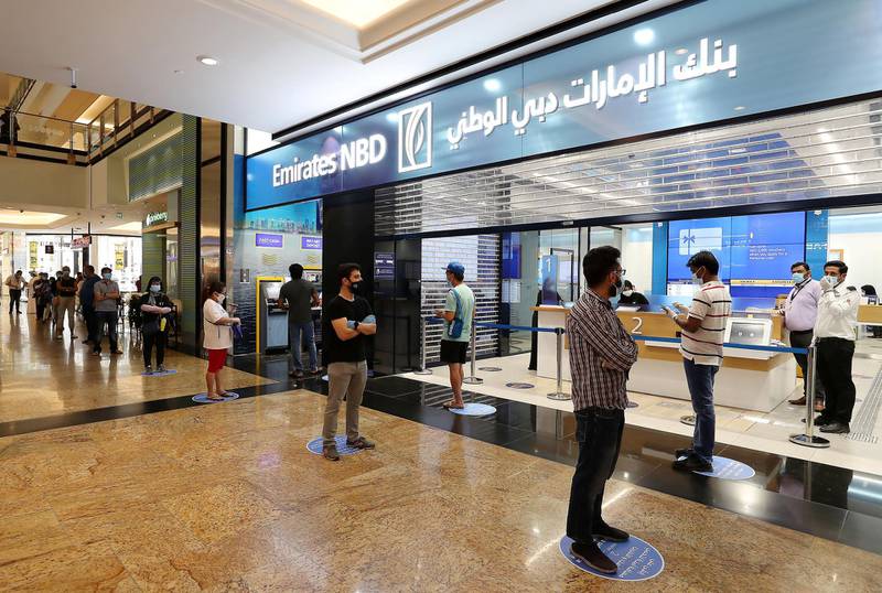 DUBAI, UNITED ARAB EMIRATES , April 29 – 2020 :- People standing in a queue at the Emirates NBD bank and wearing protective face mask and gloves to prevent the spread of the coronavirus at Mall of the Emirates in Dubai. Authorities ease the restriction for the residents in Dubai. At present mall opening timing is 12:00 pm to 10:00 pm. Carrefour timing is 9:00 am to 10:00 pm. (Pawan Singh / The National) For News/Standalone/Online. Story by Patrick