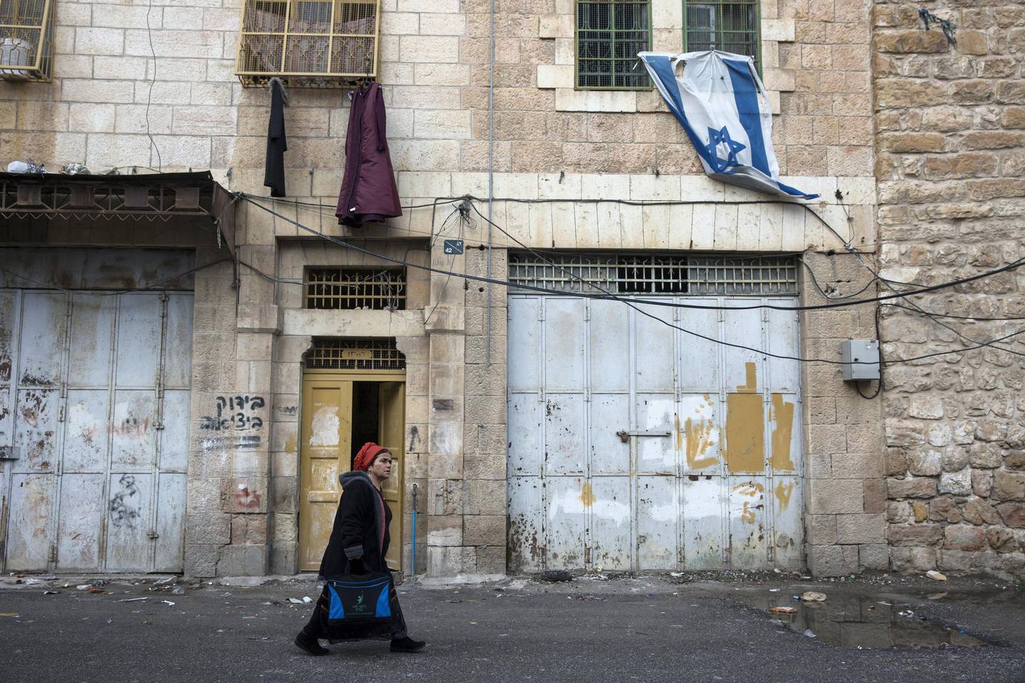 A Jewish settler walks past a street of closed Palestinian shopsin the divided area of the West Bank city of Hebron where about 900 Jewish Settlers now live on September 27,2018. The area is often to referred to as a ghost town as the presence of the settlers has restrained the freedom of movement of the thousands of Palestinians that live in the area .(Photo by Heidi Levine for The National).