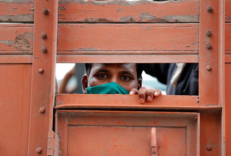 A man looks on as migrant laborers returning from other states, many of whom have been walking and hitchhiking travel on the back of a truck as they try to reach their native villages in Prayagraj, India. AP Photo