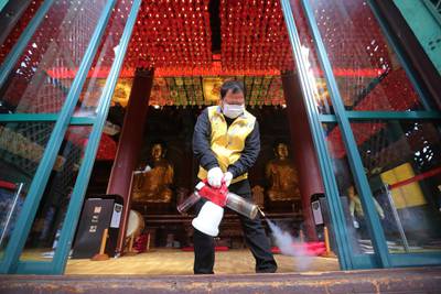 A resident of Jongno-Gu wearing a face mask sprays disinfectant as a precaution against the coronavirus at the Jogyesa Buddhist temple in Seoul, South Korea.  AP