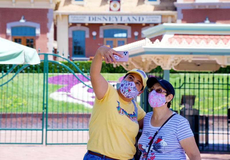 Maria Delgadillo takes a selfie with her mother Rosa Torres at the entrance to Disneyland on the reopening day of the Downtown Disney District on its reopening day in Anaheim, Calif.  AP