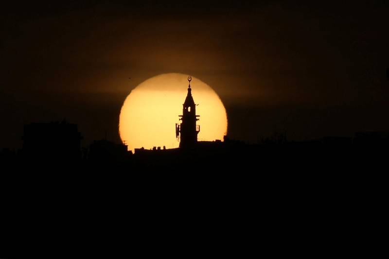 The sun sets behind a mosque minaret during Ramadan in Amman, Jordan. Reuters