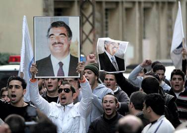 Supporters of former Lebanese prime minister Rafiq Hariri waves his pictures following Hariri's death outside his house in Beirut 14 February 2005. Hariri was killed in a huge explosion in central Beirut. AFP PHOTO/JOSEPH BARRAK (Photo by JOSEPH BARRAK / AFP)