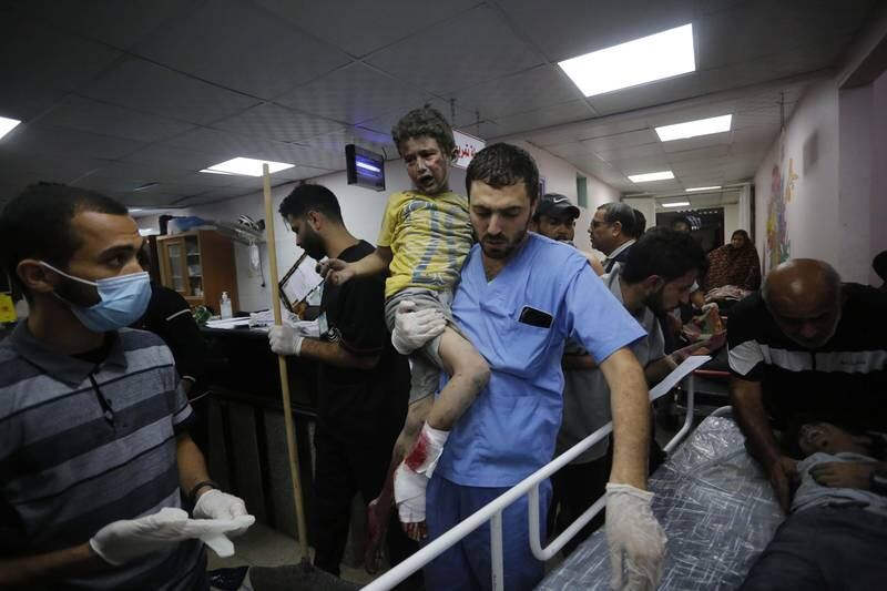 A health worker carries an injured Palestinian child in Al Aqsa hospital after Israeli airstrikes in Deir El Balah, Gaza. Reuters 