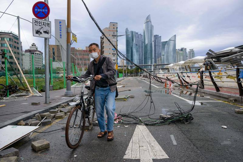 A man pushes his bicycle underneath an electric cable along a road in Busan. AFP