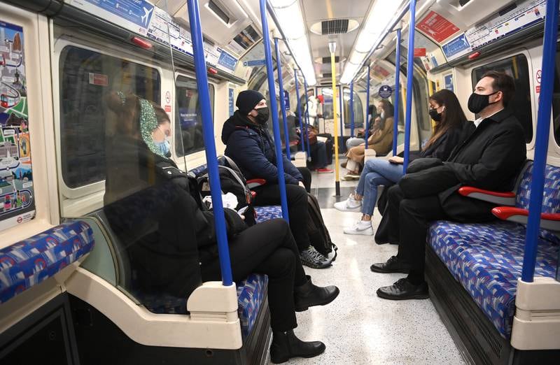 Passengers on an underground train in London. Although it is no longer legally compulsory to wear masks in indoor venues, some rail companies in England still require passengers to wear face coverings. EPA