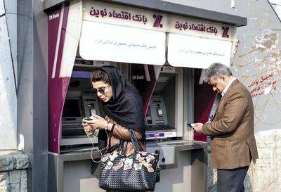 Iranians withdraw money from an ATM machine at a Bank Eghtesad Novin, on the first anniversary of the nuclear agreement, in the capital Tehran on Jaunary 14, 2017. - The first anniversary, of the nuclear deal between Iran and six powers, that lifted a large part of international sanctions on Iran in return for limits on Tehran's nuclear programme, comes four days before the inauguration of Republican president Trump on January 20. (Photo by ATTA KENARE / AFP)