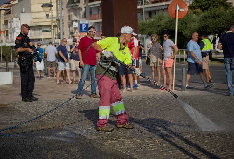A municipal worker washes the pavement on the spot where terrorist were shot by police in Cambrils, Spain, Friday, Aug. 18, 2017. Spanish police on Friday shot and killed five people carrying bomb belts who were connected to the Barcelona van attack that killed at least 13, as the manhunt intensified for the perpetrators of Europe's latest rampage claimed by the Islamic State group. (AP Photo/Emilio Morenatti)