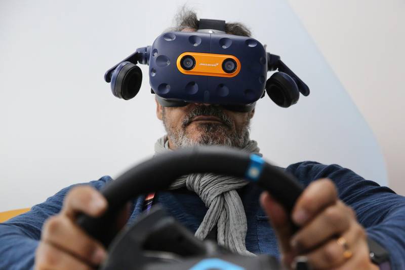 An attendee wears a McLaren branded HTC Vive Pro headset and sits inside a driving module to play a virtual reality (VR) F1 racing game on day two of the MWC. Bloomberg