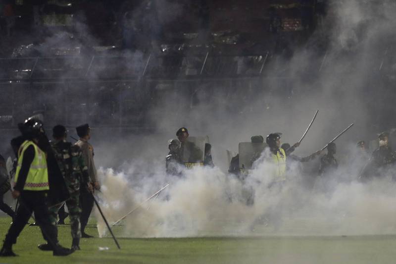 Police officers and soldiers stand amid tear gas smoke after the match at Kanjuruhan Stadium. AP