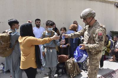 A Turkish soldier offers water to Turkish nationals waiting to board an air force plane at Kabul airport last Wednesday. AP Photo