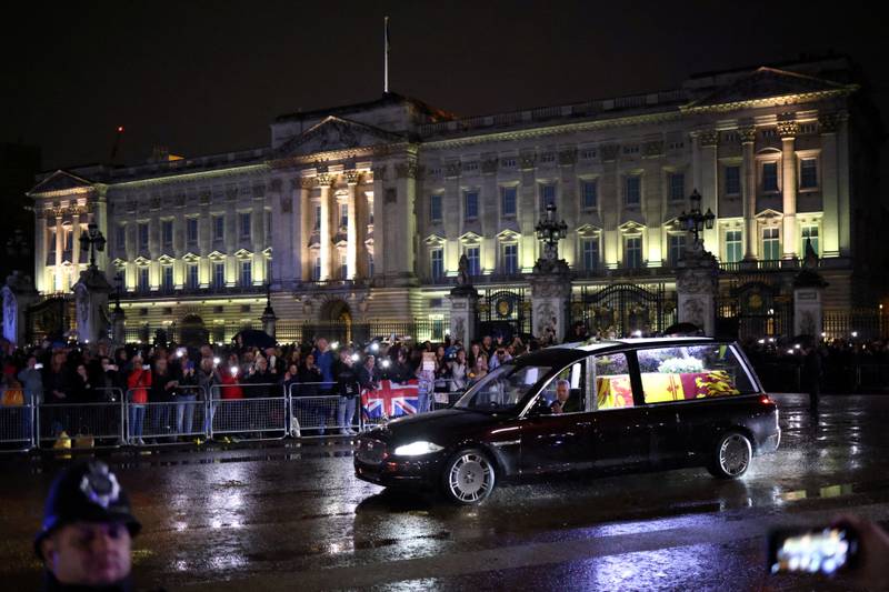 Interior lights shine brightly in the gloomy London evening, illuminating the coffin draped in a royal standard. Reuters